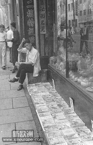 1949年5月,上海武侠书地摊,安静如常,店主拿着书,看着镜头.jpg